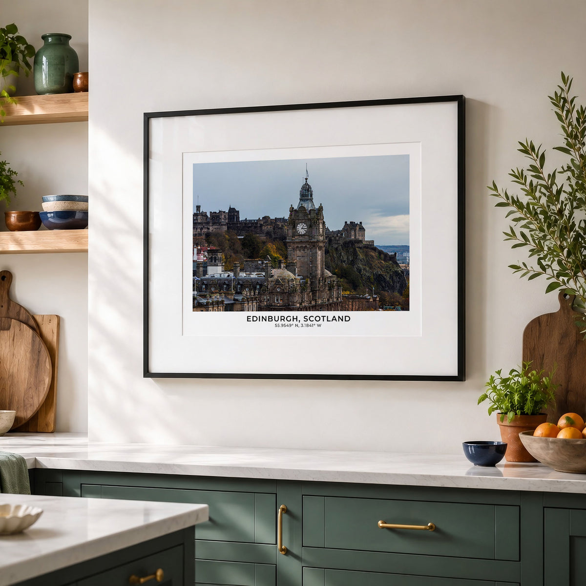 A framed art print of Edinburgh, Scotland, featuring the historic Edinburgh Castle, displayed on a warm off-white wall in a styled kitchen setting with green cabinets and wooden accents.