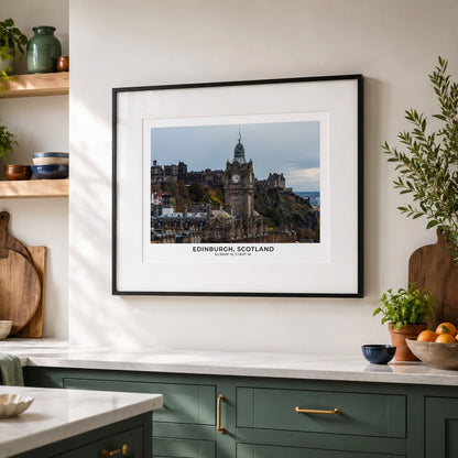 A framed art print of Edinburgh, Scotland, featuring the historic Edinburgh Castle, displayed on a warm off-white wall in a styled kitchen setting with green cabinets and wooden accents.